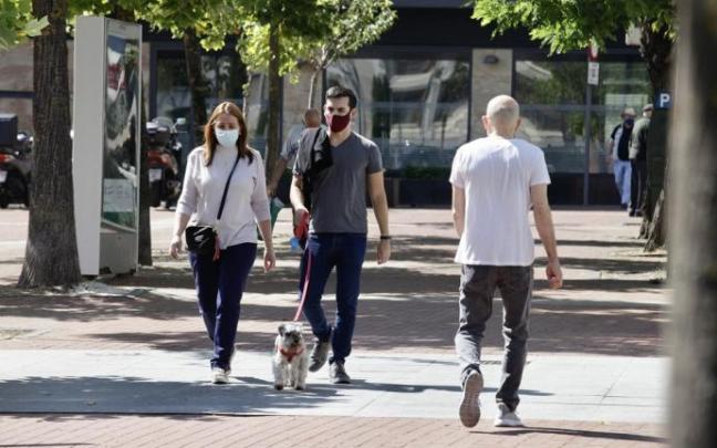 Personas andando por la calle con mascarilla.