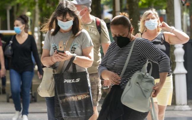 Personas andando por la calle con mascarilla.