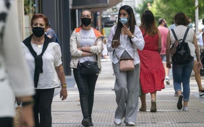 Personas andando por la calle con mascarilla.