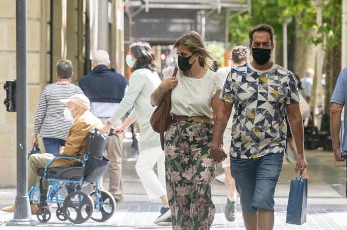 Personas andando por la calle con mascarilla.
