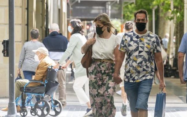 Personas andando por la calle con mascarilla.