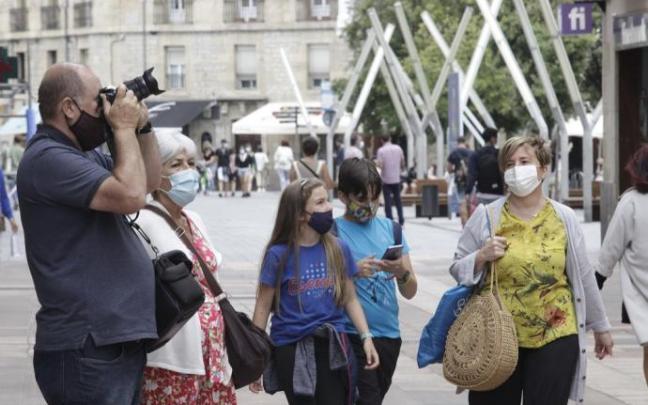 Personas andando por la calle con mascarilla.