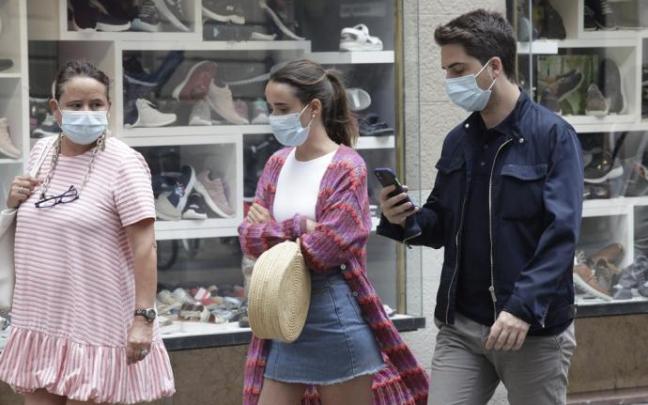 Personas andando por la calle con mascarilla.