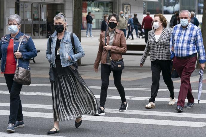 Personas andando por la calle con mascarilla.