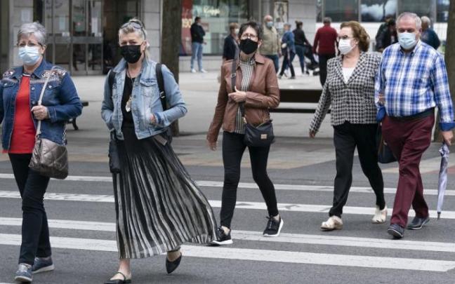 Personas andando por la calle con mascarilla.