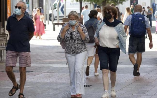 Varias personas andando por la calle con mascarilla.