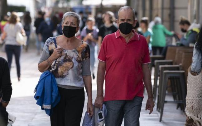 Varias personas andando por la calle con mascarilla.