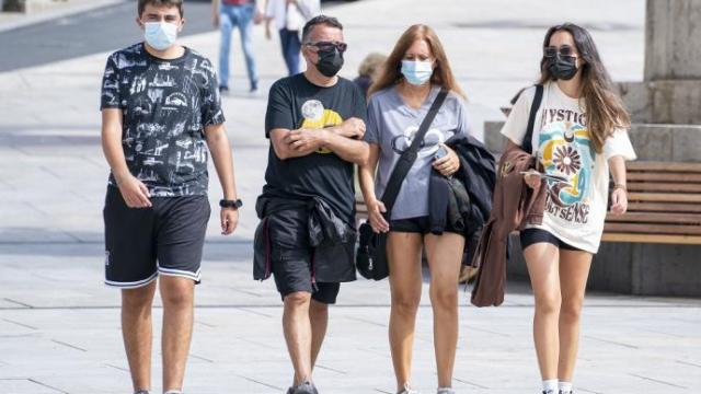 Varias personas andando por la calle con mascarilla.