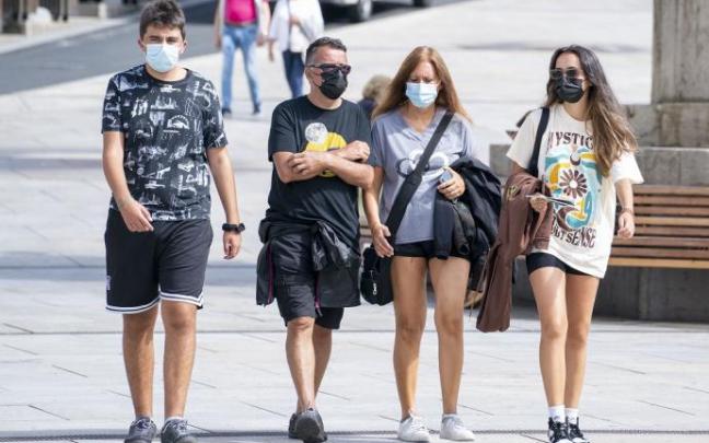 Varias personas andando por la calle con mascarilla.