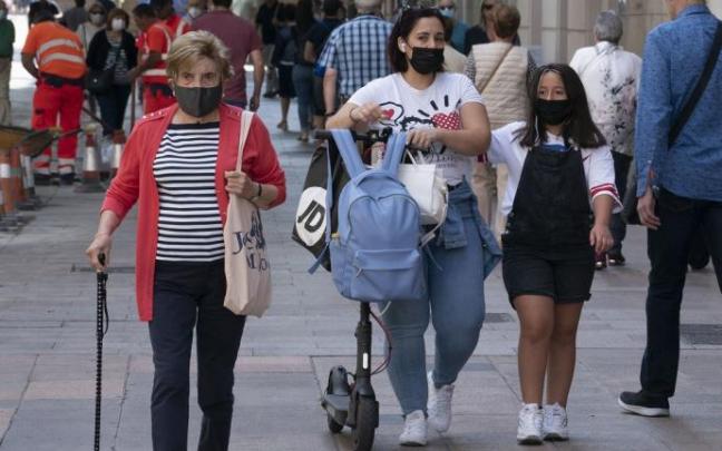Varias personas andando por la calle con mascarilla.
