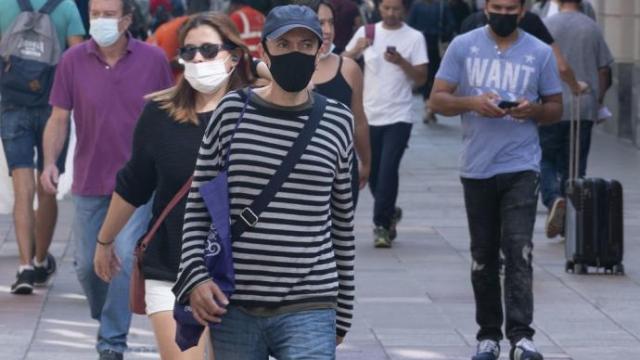 Varias personas caminan por la calle con mascarilla. Varias personas caminan por la calle con mascarilla.