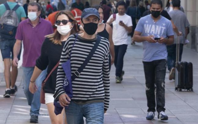 Varias personas caminan por la calle con mascarilla. Varias personas caminan por la calle con mascarilla.