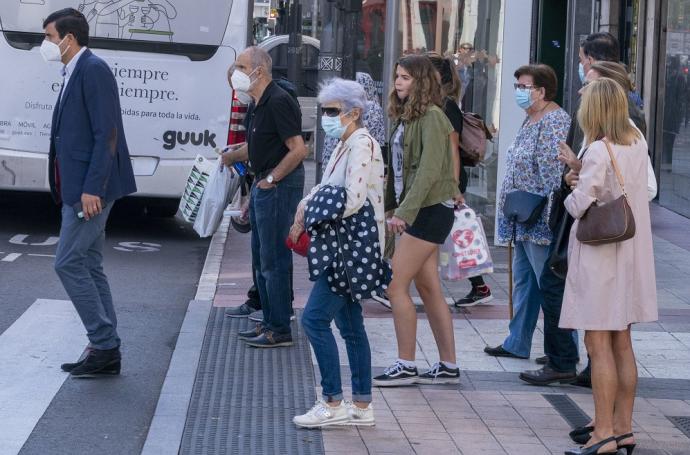 Varias personas paseando por la calle con mascarilla.