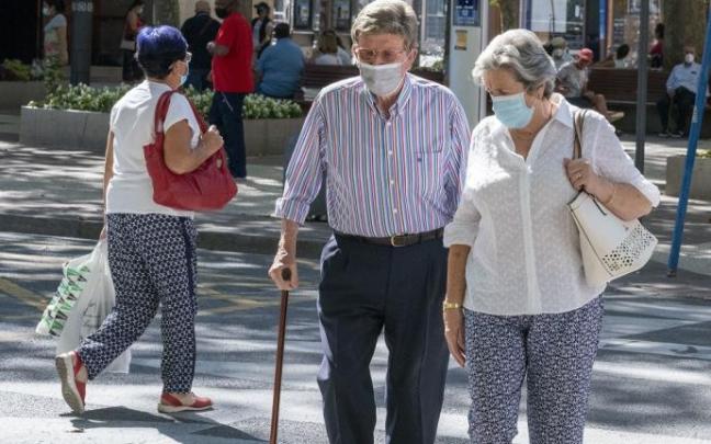 Varias personas andando por la calle con mascarilla.