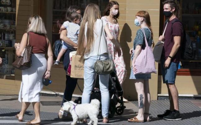 Personas andando por la calle con mascarilla.