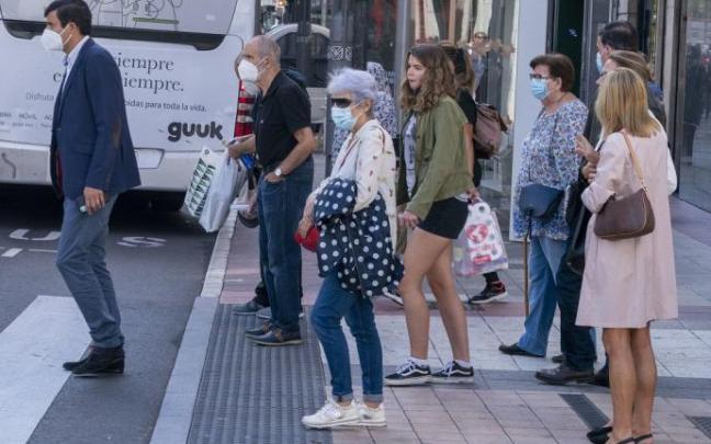 Varias personas andando por la calle con mascarilla.
