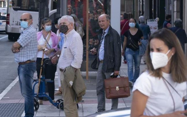 Varias personas andando por la calle con mascarilla.