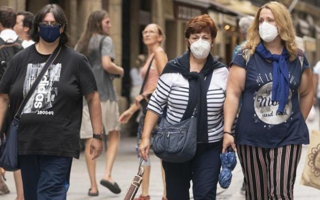 Varias personas andando por la calle con mascarilla.