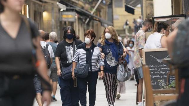 Personas andando por la calle con mascarilla.