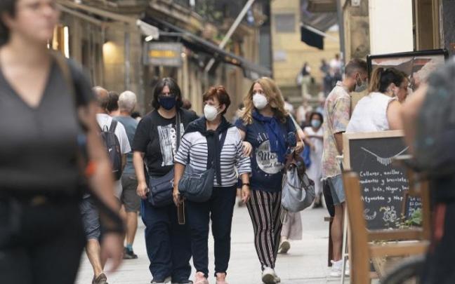 Personas andando por la calle con mascarilla.
