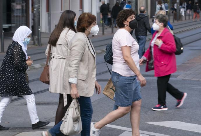Varias personas andando por la calle con mascarilla.