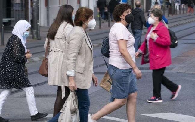 Varias personas andando por la calle con mascarilla.