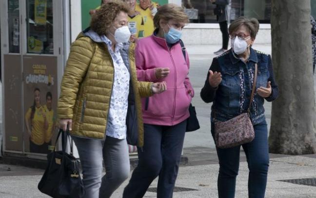 Personas andando por la calle con mascarilla.