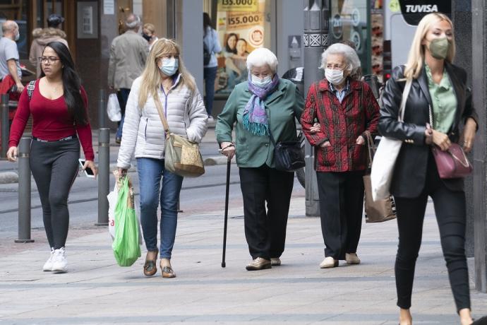 Personas andando por la calle con mascarilla.