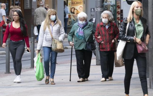 Personas andando por la calle con mascarilla.