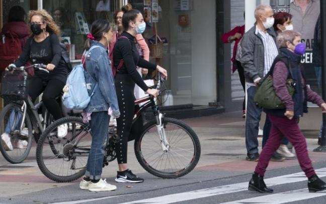 Varias personas andando por la calle con mascarilla.