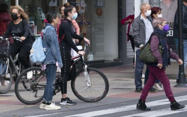 Varias personas andando por la calle con mascarilla.