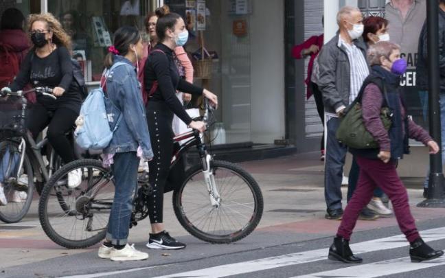 Personas andando por la calle con mascarilla.