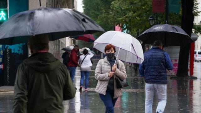 Varias personas caminando por la calle con mascarilla.