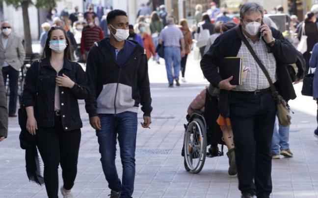 Personas andando por la calle con mascarilla.