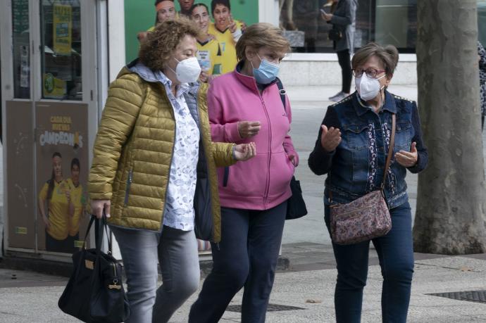 Personas andando por la calle con mascarilla.