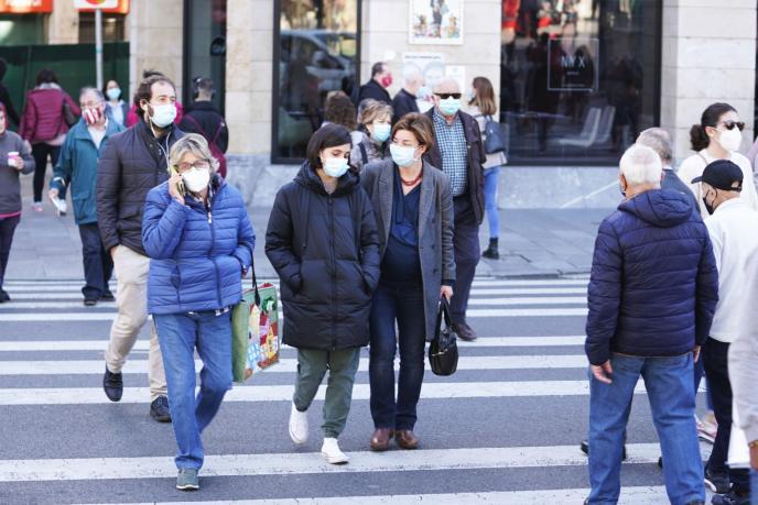 Gente paseando por la calle con mascarilla.