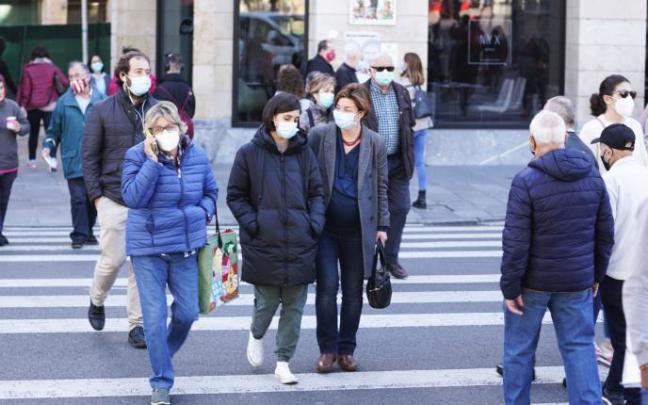 Gente paseando por la calle con mascarilla.