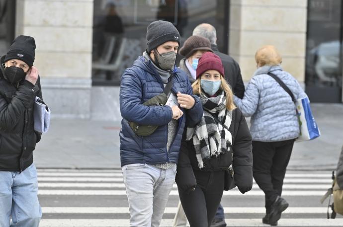 Varias personas caminando por la calle con mascarilla.