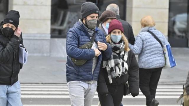Varias personas caminando por la calle con mascarilla.