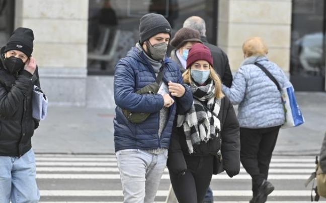 Varias personas caminando por la calle con mascarilla.
