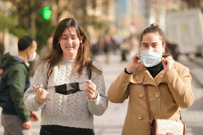 Dos jóvenes se quitan la mascarilla.