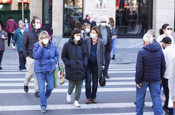 Gente paseando por la calle con mascarilla.