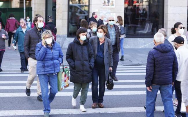 Gente paseando por la calle con mascarilla.