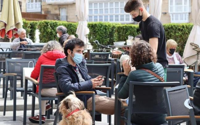 Personas sentadas en la terraza de un bar con mascarilla.