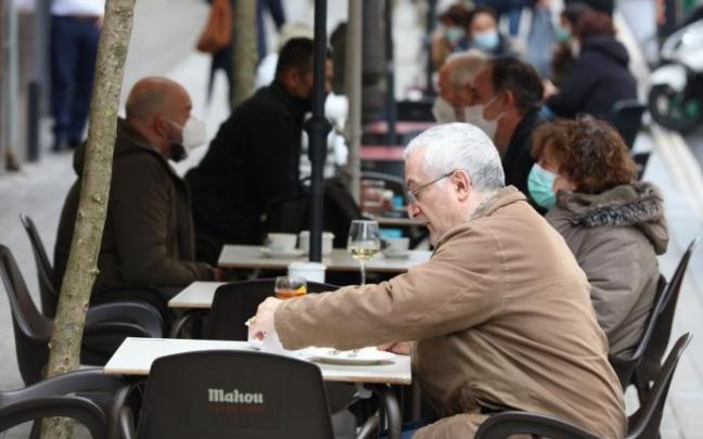 Varias personas disfrutan del buen tiempo en una terraza.