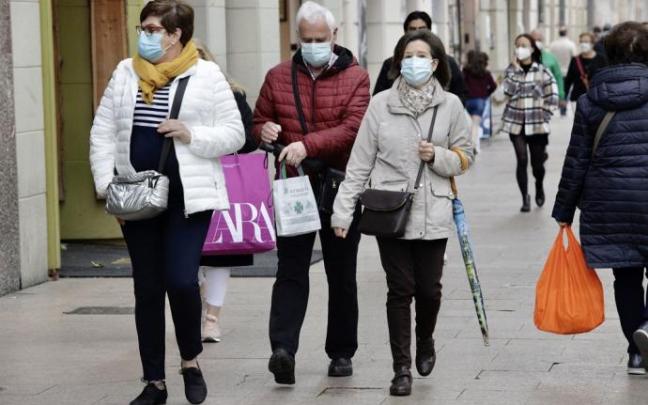 Varias personas andando por la calle con mascarilla.