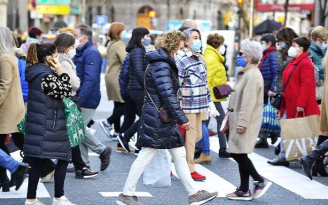 Varias personas cruzan un paso de peatones.