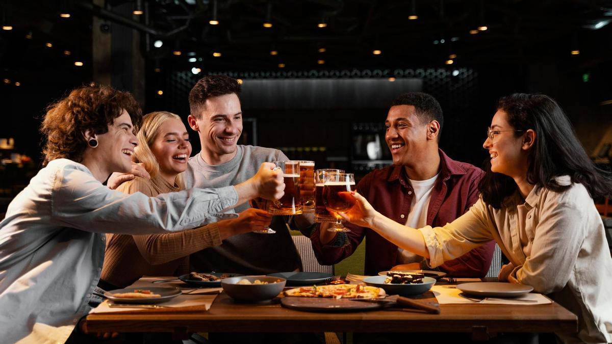 Un grupo de amigos brinda con cerveza en un bar.