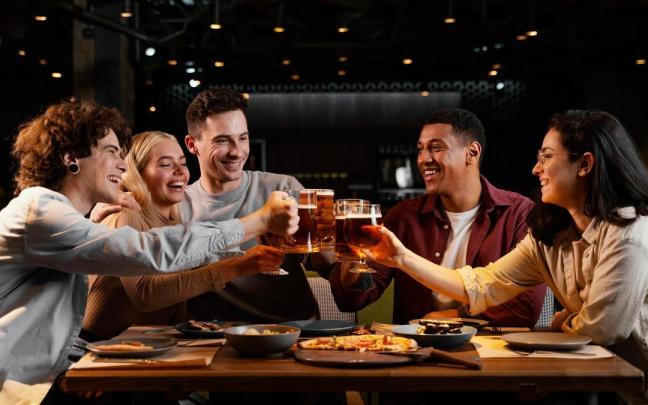 Un grupo de amigos brinda con cerveza en un bar. Un grupo de amigos brinda con cerveza en un bar.