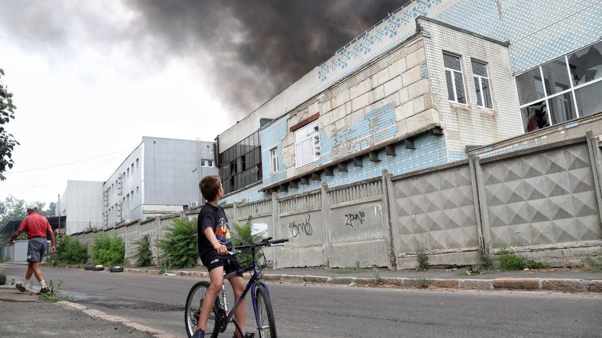 Un niño mira una columna de humo que se eleva sobre un almacén comercial e industrial en Odesa.